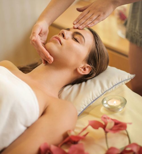 Woman in Wrapped in White Towel Lying on Bed Getting Massage